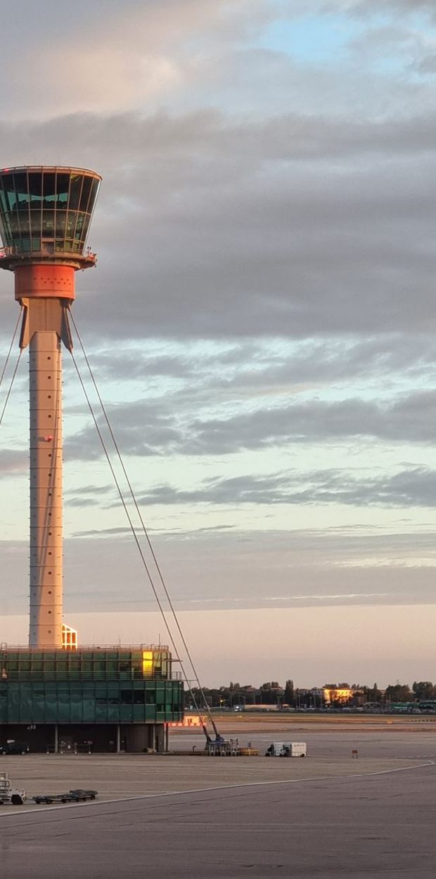 The control tower at London Heathrow Airport lit by dusk light above the apron